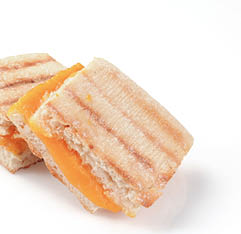 A grilled cheese panini on ciabatta bread on white wth a natural drop shadow