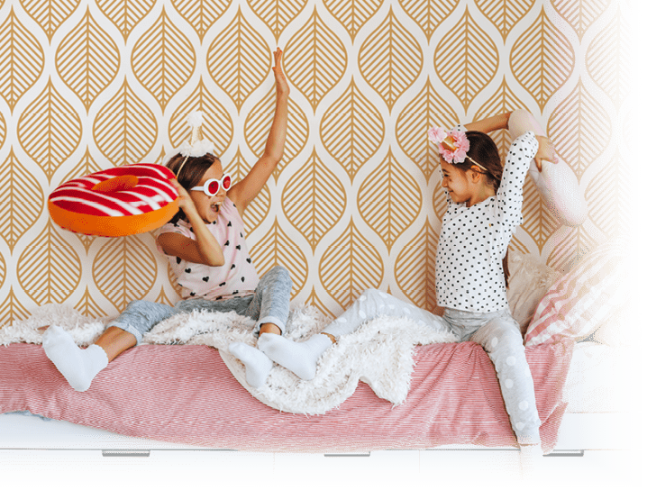 Two children playing together in bed, having fun in bright girly playroom  Kids paljamas party in white bedroom interior 