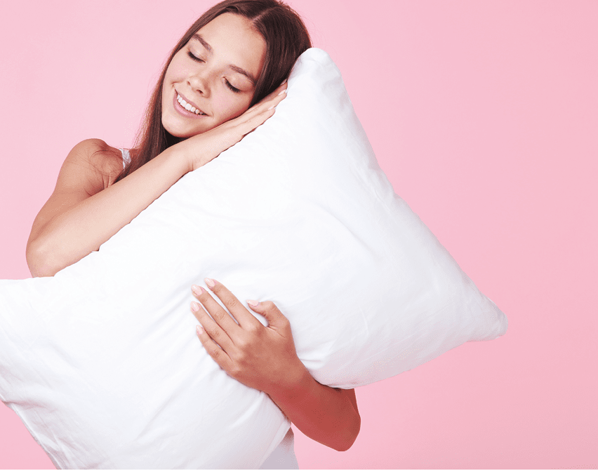 Young girl with white pillow on pink background