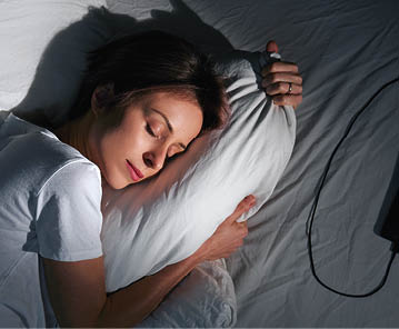 Young woman hugging pillow in bed, top view.