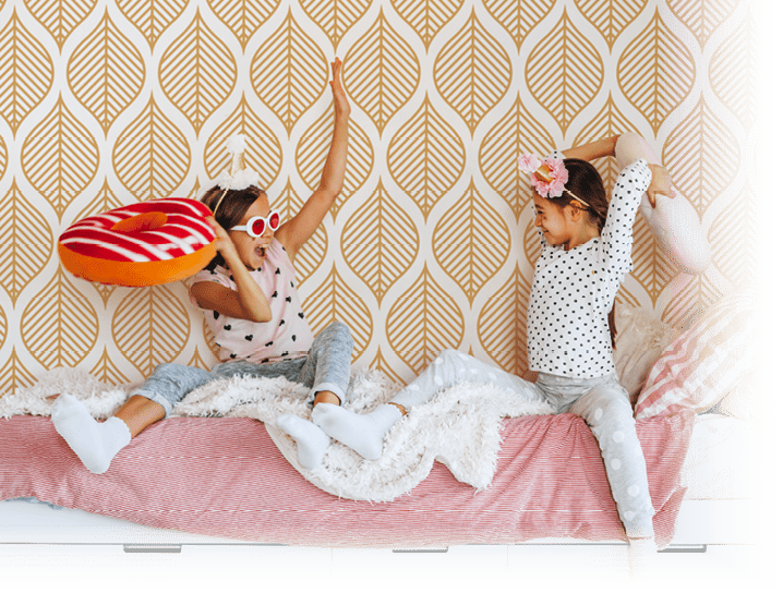 Two children playing together in bed, having fun in bright girly playroom  Kids paljamas party in white bedroom interior 