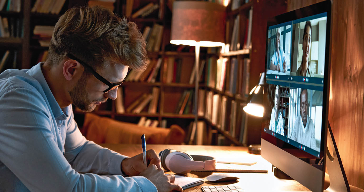 Young business man video conference calling using computer social distance working from home office. Remote male professional videoconferencing by virtual team online web meeting group chat.