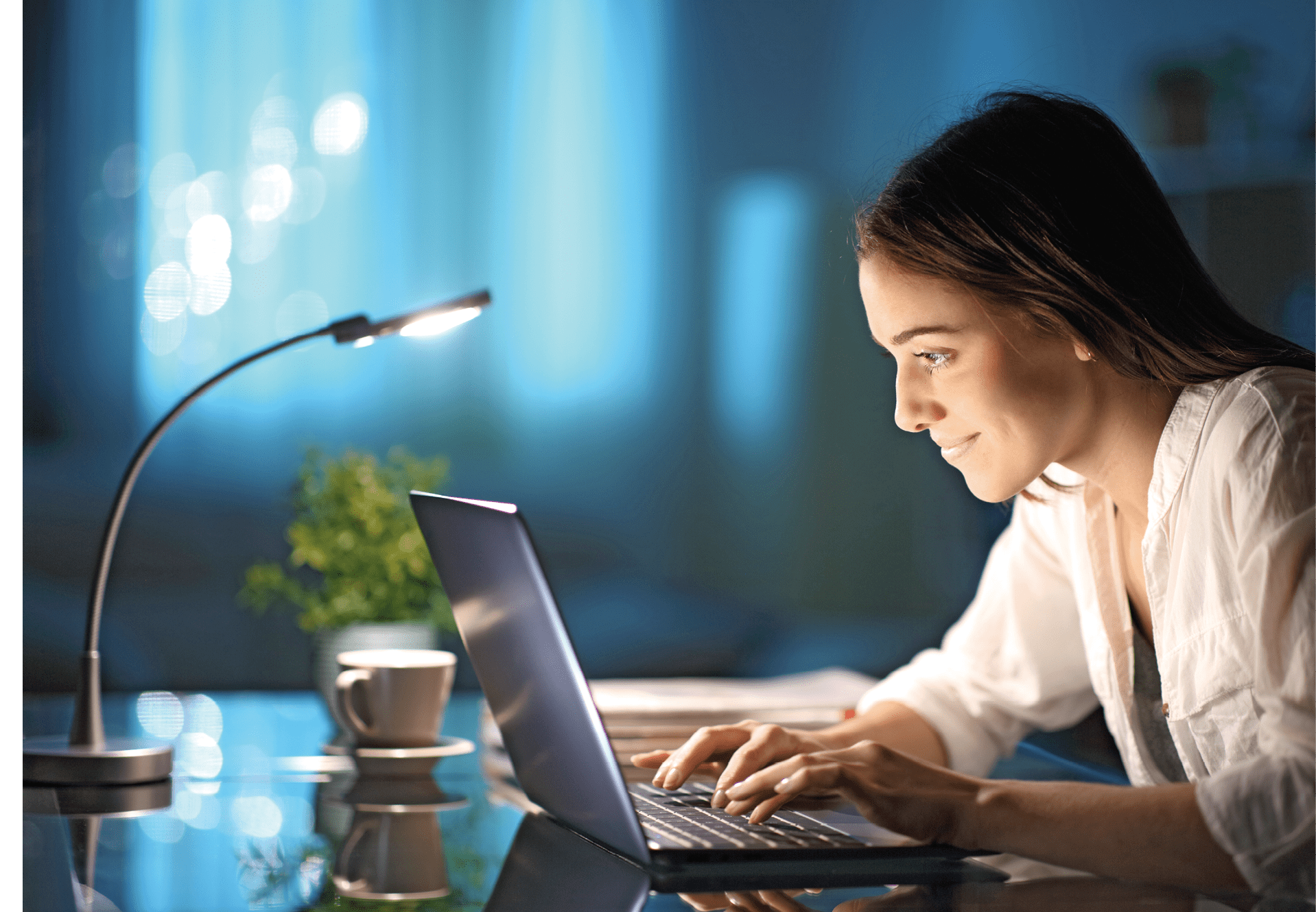 Happy woman writing on laptop keyboard in the night