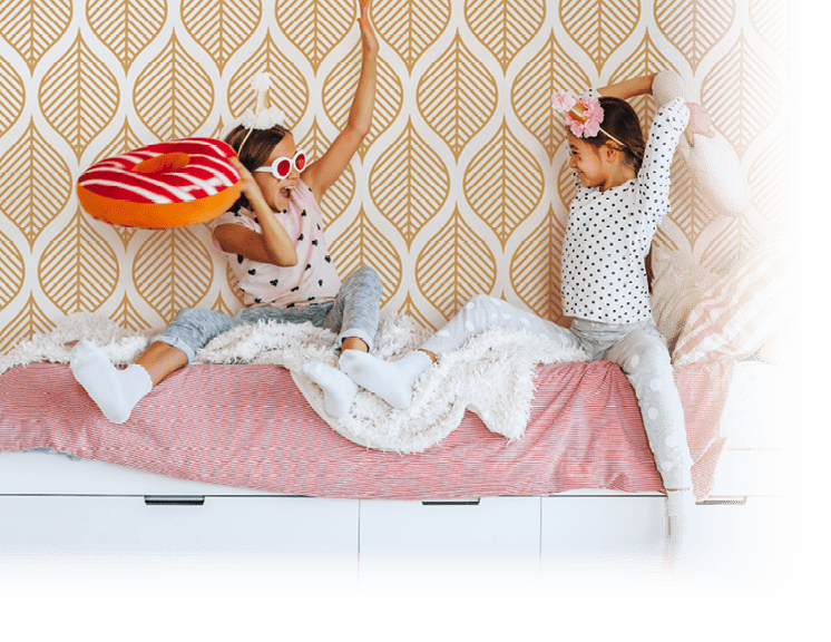 Two children playing together in bed, having fun in bright girly playroom  Kids paljamas party in white bedroom interior 