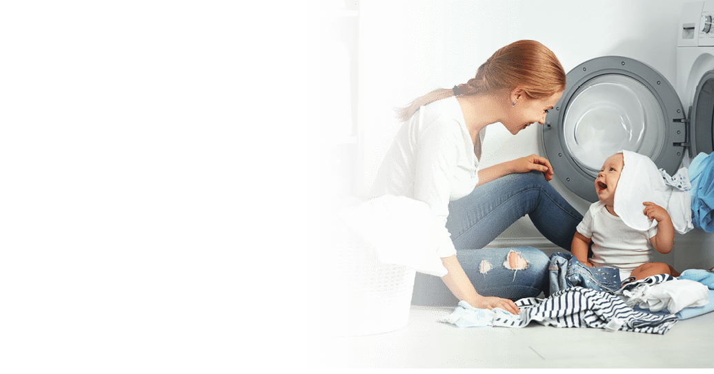 mother a housewife with a baby engaged in laundry fold clothes into the washing machine
