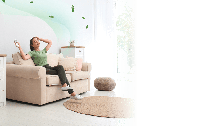 Happy young woman switching on air conditioner with remote control at home