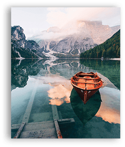 On the pier. Wooden boat on the crystal lake with majestic mountain behind. Reflection in the water.