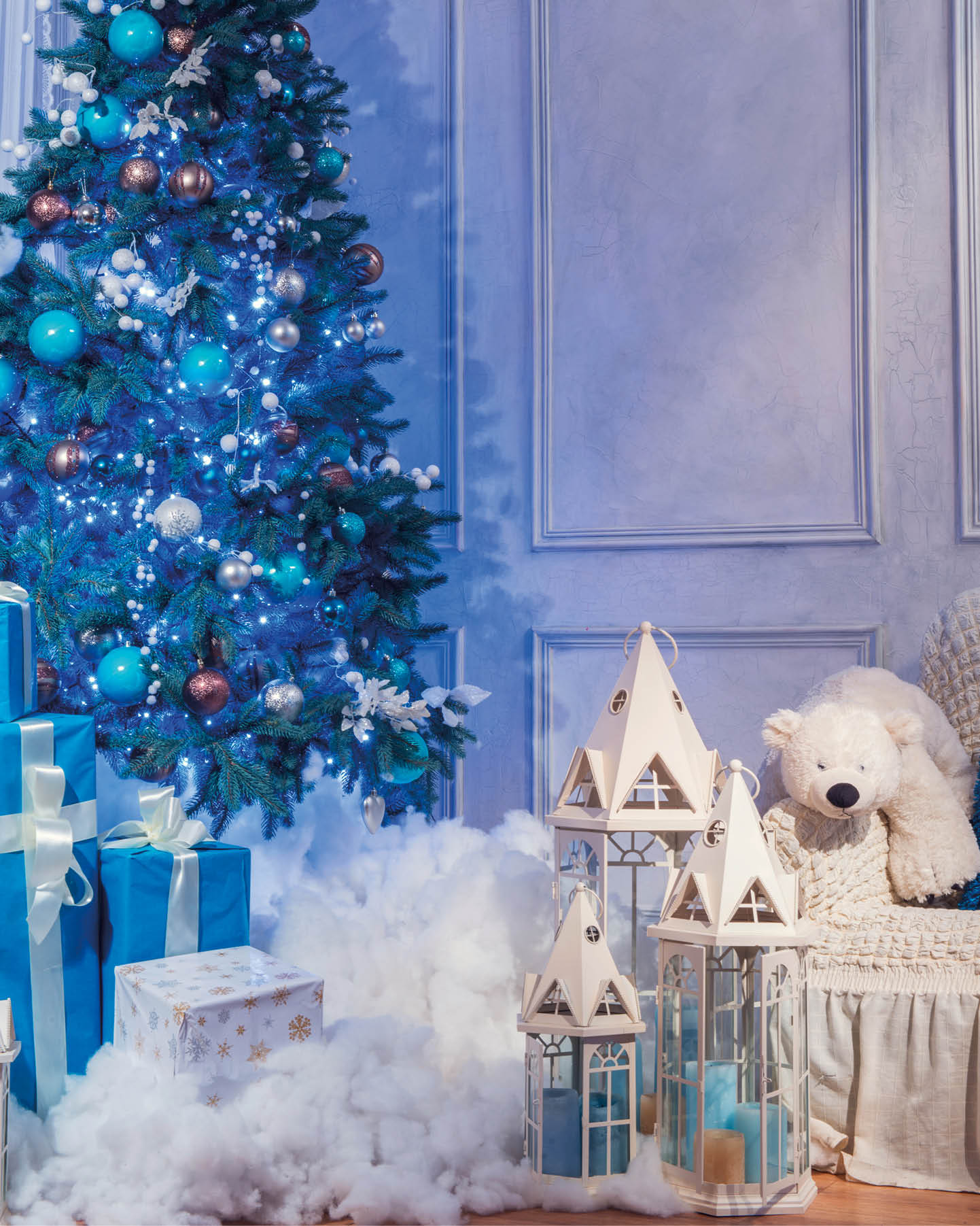 Christmas interior. Beautifully decorated Christmas interior with high blue fur tree surrounded by white lanterns, candles and wrapped presents covered with decorative snow