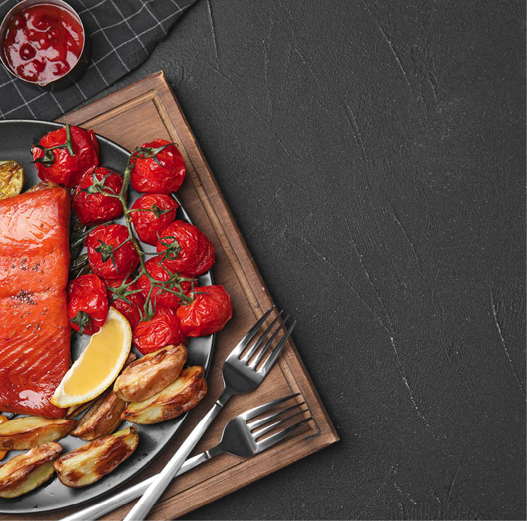 Tasty cooked salmon and vegetables served on black table, flat lay with space for text. Healthy meals from air fryer
