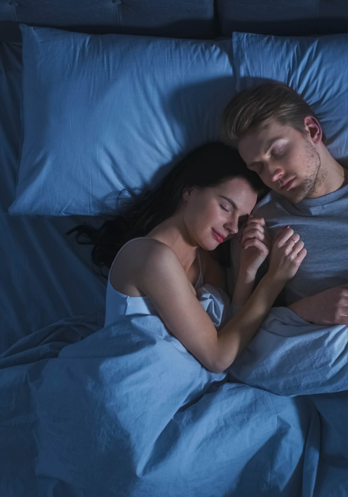 Happy Young Couple Cuddling Together in the Bed Sleeping at Night. Beautiful Girl and Handsome Boy Sleeping Together, Sweetly Embracing Each other. Top Down Shot.