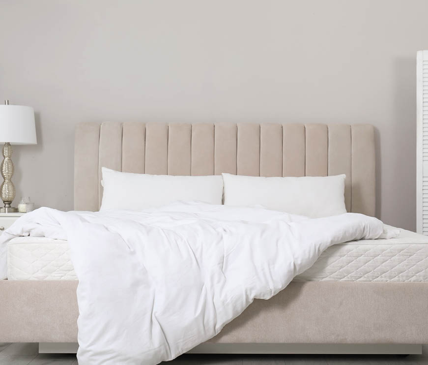Comfortable bed with soft white mattress, blanket and pillows indoors