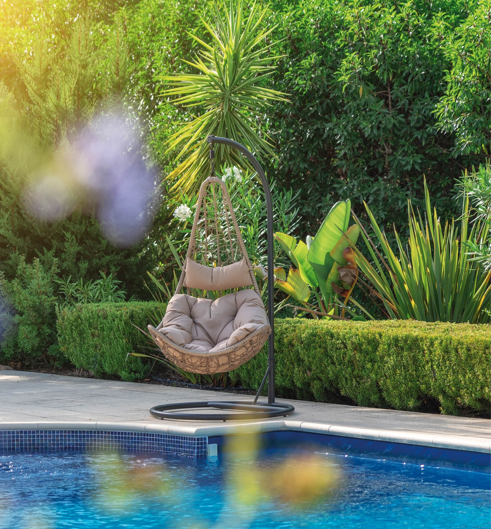 Luxurious pool in the garden of a private villa, hanging chair with pillows for leisure tourists, in summer. Portugal, Algarve