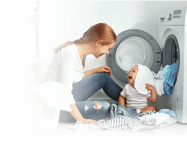 mother a housewife with a baby engaged in laundry fold clothes into the washing machine