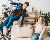 caucasian teen boy jumping over sofa at home