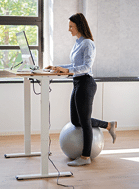 Woman Using Adjustable Height Standing Desk In Office For Good Posture