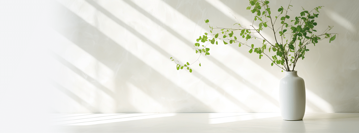 Green branch of tree with shadow against white marble tile wall and wood table with copy space in the spring sunlight