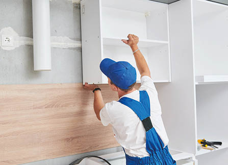 kitchen installation. Worker assembling furniture set. Hanging cabinet on wall