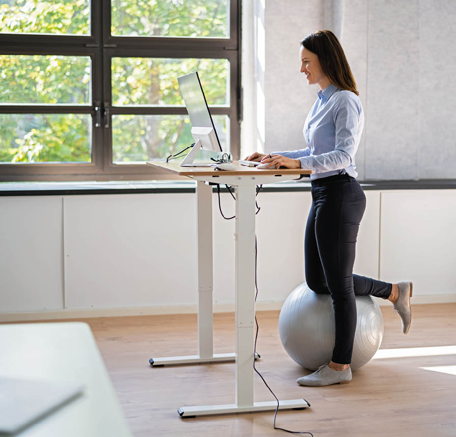 Woman Using Adjustable Height Standing Desk In Office For Good Posture