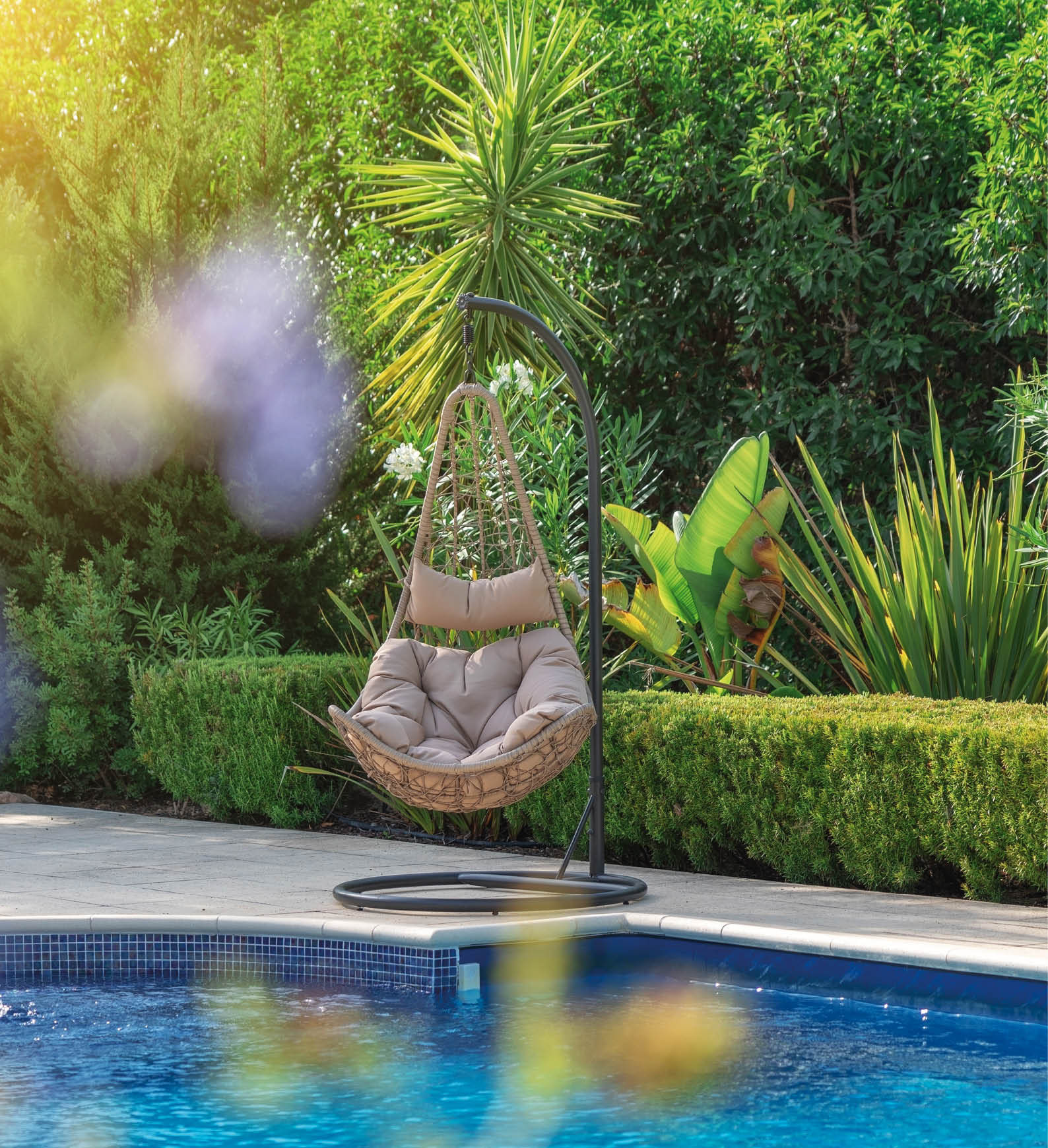 Luxurious pool in the garden of a private villa, hanging chair with pillows for leisure tourists, in summer. Portugal, Algarve