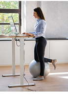 Woman Using Adjustable Height Standing Desk In Office For Good Posture