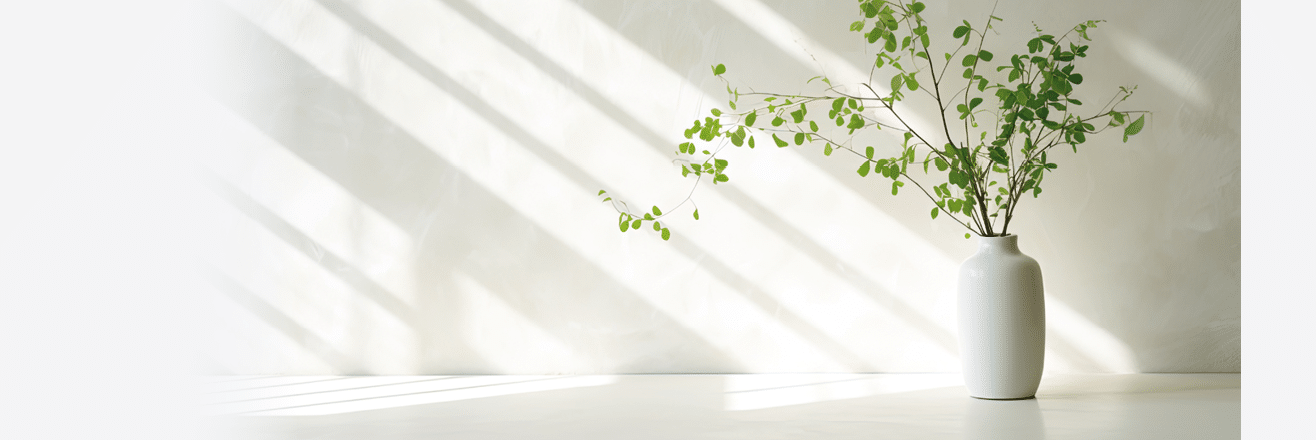 Green branch of tree with shadow against white marble tile wall and wood table with copy space in the spring sunlight
