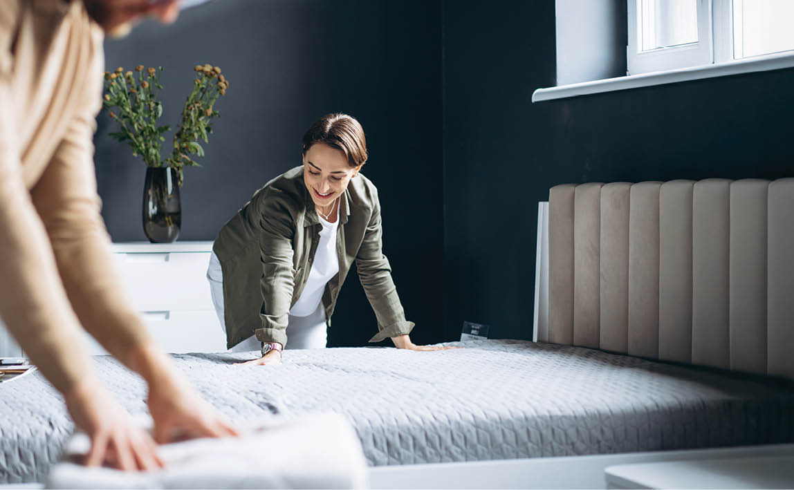 Couple buying new bed with orthipedic mattress in furniture store