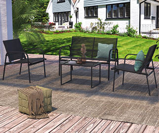 A patio set with four chairs and a table is arranged on a wooden deck. The chairs are black and the table is glass. The patio set is located in front of a house. AI generated content