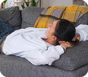 A woman at home in a white interior Lying on couch and watches TV. Home recreation, leisure