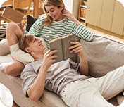 A young couple enjoys reading books on a comfortable sofa in their beautifully styled living space.