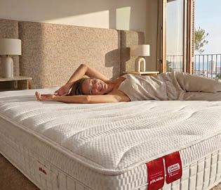 A woman is lying on a bed with a white mattress. AI generated content
