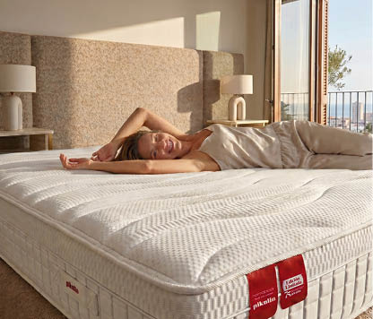 A woman is lying on a bed with a white mattress. AI generated content