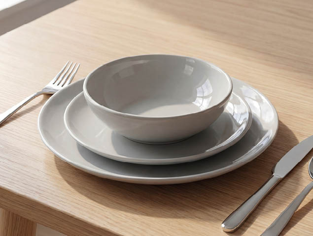 A wooden dining table with a bowl, spoon, fork, and knife on it. AI generated content