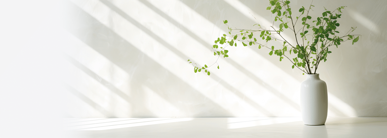 Green branch of tree with shadow against white marble tile wall and wood table with copy space in the spring sunlight