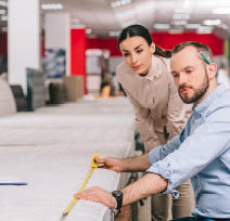 couple measuring mattress with measure tape in furniture store with arranged mattresses