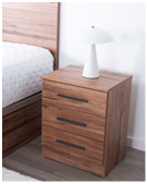 A wooden nightstand with three drawers and black handles is placed next to a bed with a white mattress, and a white modern lamp sits on top of the nightstand against a white wall. Description generated by AI