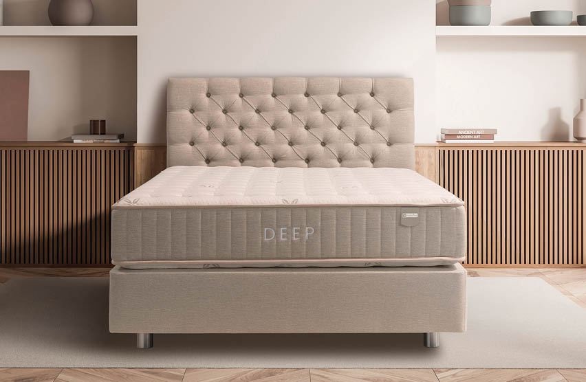 A neatly made beige upholstered bed with a tufted headboard is centered in a modern bedroom featuring wooden slatted cabinets and minimalist decor. Description generated by AI