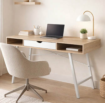 A modern minimalist wooden desk with white metal legs holds a laptop, books, a small plant, a white lamp, and a cup with pencils, accompanied by a beige upholstered swivel chair on a light wood floor. Description generated by AI
