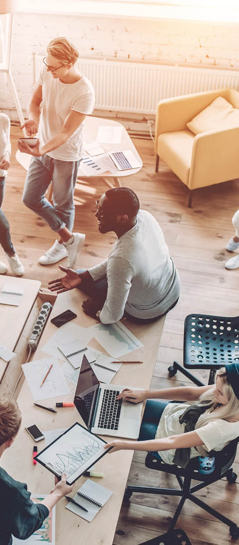 Top view of multiracial young creative people in modern office. Group of young business people are working together with laptop, tablet, smart phone, notebook. Successful hipster team in coworking. Freelancers.