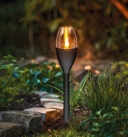 A small lighted candle is placed in a garden setting. AI generated content