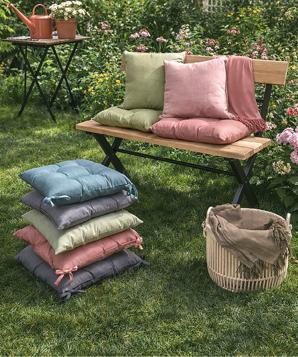 A wooden bench with pillows on it is placed in a garden setting. AI generated content